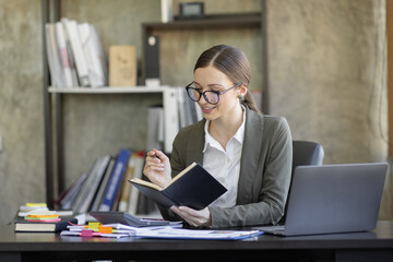 Portrait of smiling pretty young business woman in wearing glasses sitting on her workplace office, business finance concept.