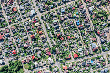 suburb with colorful houses roofs, green trees, yards and roads. aerial photo.