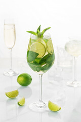 Classic cocktail mix mohito in glass on white background with lime, lemon, mint, soda,  alcohol