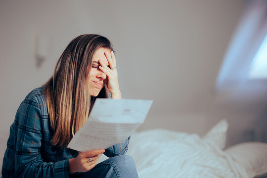 Unhappy Woman Reading a Document at Home. Stressed homeowner receiving bad news in formal letter
