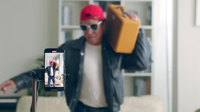 Funny Senior Asian man dj tiktoker created his dancing video by smartphone camera. To share video on social media application