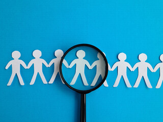 Magnifying glass and figurines of people searching for job candidates