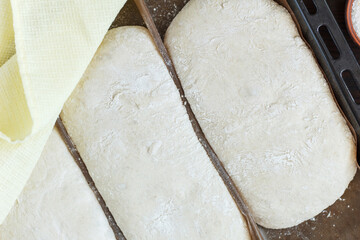 fresh raw dough for baking bread on a baking sheet, ready for baking on a wooden background. Close-up