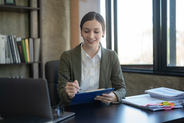 Smiling professional businesswoman working with a laptop in an office.