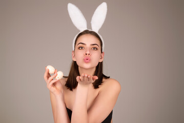 Woman with bunny ears and easter eggs. Easter bunny isolated on studio background. Holidays, spring and party concept. Portrait of cute girl celebrating Easter.
