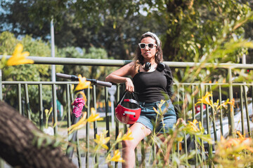 woman wearing shorts holding a helmet leaning on a fence in an urban setting