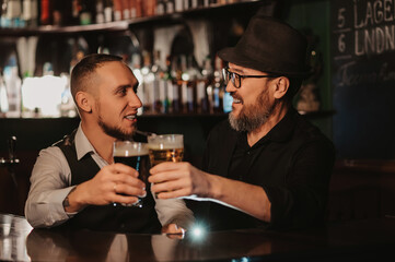 two happy smiling bartenders clink glasses of draft beer at bar counter