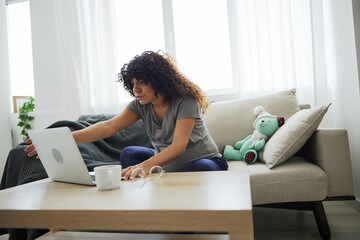 A pregnant woman smile sits at home on the sofa with a laptop and watches tv shows movies and series. Lifestyle of a pregnant woman, preparation for childbirth, last month of pregnancy