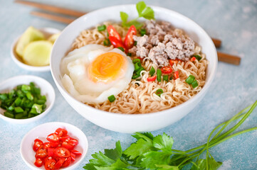 instant noodles cooking tasty eating with bowl, noodles bowl with boiled egg minced pork vegetable spring onion lemon lime lettuce celery and chili on table food, noodle soup