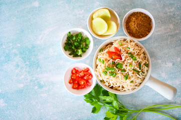 instant noodles cooking tasty eating with bowl, noodles bowl with vegetable spring onion lemon lime lettuce celery and chili on table food, noodle soup