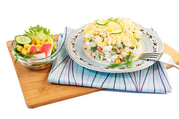 On a beautiful dish, fresh vegetable salad with crab sticks, sweet corn, cheese,fresh cucumber, boiled eggs, dill, mayonnaise.