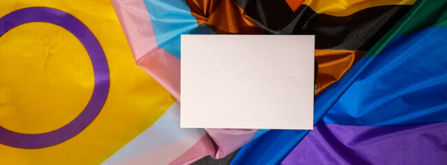 Banner Empty paper blank on Rainbow LGBTQIA flag made from silk material. Mock up template copy...