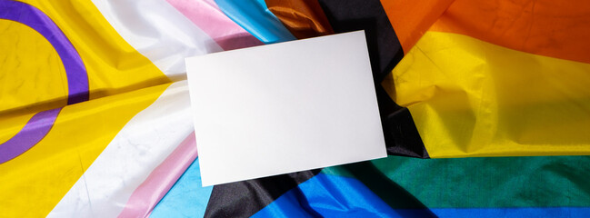Banner Empty paper blank on Rainbow LGBTQIA flag made from silk material. Mock up template copy...