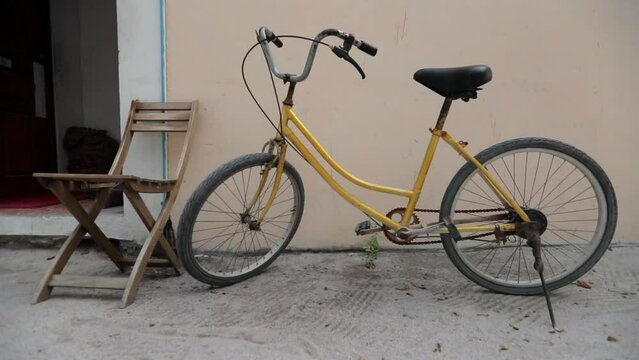 Slow Motion Shot Of Bicycle By Empty Wooden Chair Against House - Thulusdhoo, Maldives