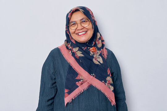 Smiling elderly Asian muslim woman 50s wearing hijab in glasses posing confident with smiling friendly and looking at camera isolated on white background