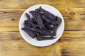 Slices of biltong (South African dried meat) on wooden table. Top view