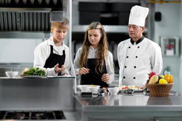 Students are learning to cook in a culinary institute with a standard kitchen and complete...