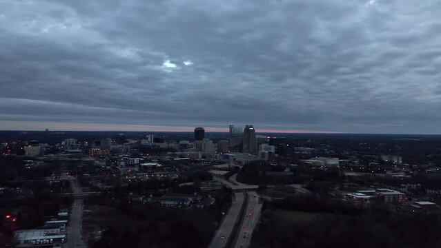 Aerial orbit around traffic near downtown Raleigh North Carolina. Night view of American city skyline.