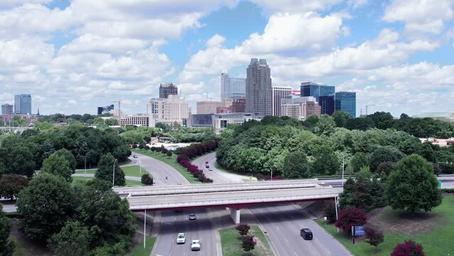 Slow motion aerial rising shot of Raleigh skyline on summer day with puffy clouds.