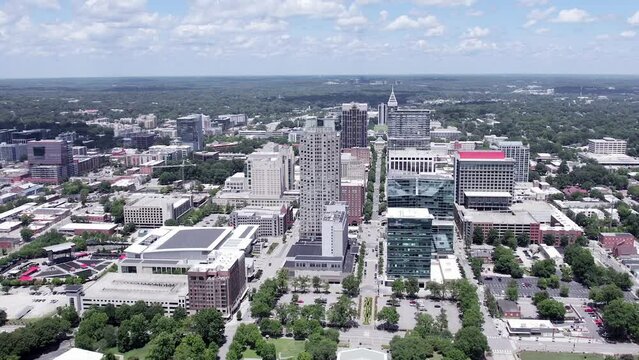 High aerial orbit around Raleigh NC skyline on beautiful summer day. North Carolina city establishing shot in America.
