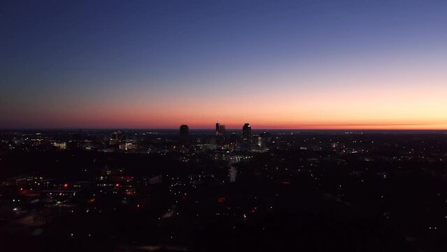 Aerial shot of American city during orange sunset. Dark urban metropolis during blue hour.