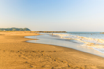 波打ち際がある遠浅の砂浜の夕方