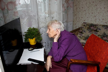 The senior woman watching tv at home.