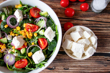 A green vegan salad made from a mix of green leaves and vegetables. On a wooden background