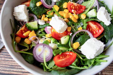 A green vegan salad made from a mix of green leaves and vegetables. On a wooden background