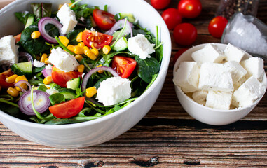 A green vegan salad made from a mix of green leaves and vegetables. On a wooden background