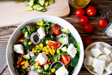 A green vegan salad made from a mix of green leaves and vegetables. On a wooden background