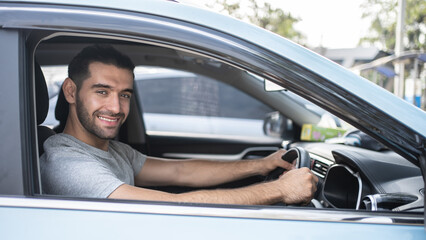 Fototapeta na wymiar Happy man driving a car and smiling. Cute young Hispanic male success happy brunette. Portrait of happy driver steering car Holiday.