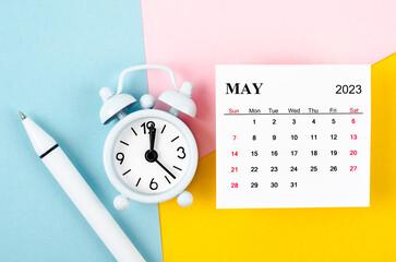 The May 2023 Monthly calendar with alarm clock and pen on beautiful background.