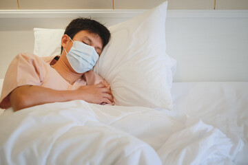 Asian male patient sleeping on bed with face mask in recovery room in hospital ward. 