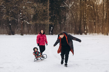 Fototapeta na wymiar A married couple with their daughter is walking through the winter forest