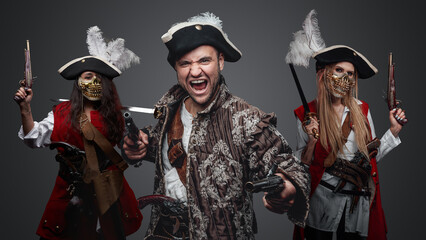 Shot of screaming pirate man and two buccaneer women with flintlock guns.