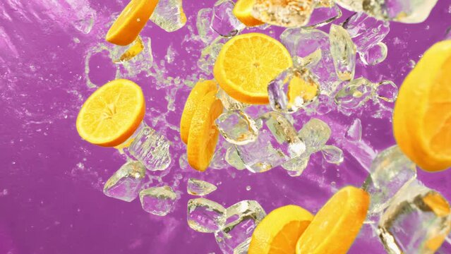 Juicy sweet orange and fly ice cube or water splash or pours drops juice in super slow motion on 1000fps.Citrus orange slices and ice fall or explode in super slow motion 1000fps on purple background