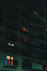 Apartment building at night, orange lights inside.