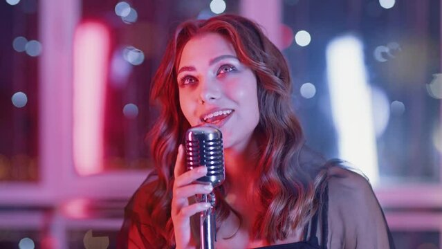 Portrait of a pretty female singing in a nightclub, party, close-up of a woman's face in neon light, singer singing on stage.