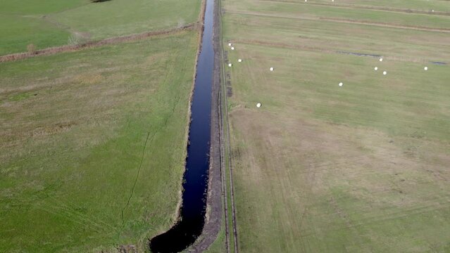 Areal drone footage of water channel and vast farming fields with autumn colors taken at place called Uetz in Brandenburg, Germany. Peaceful and tranquil atmosphere.