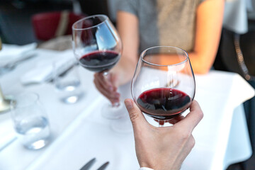 Couple of lovers with glasses of red wine sitting in restaurant
