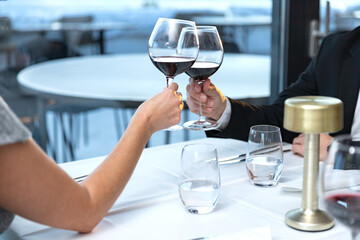 Couple of lovers with glasses of red wine sitting in restaurant