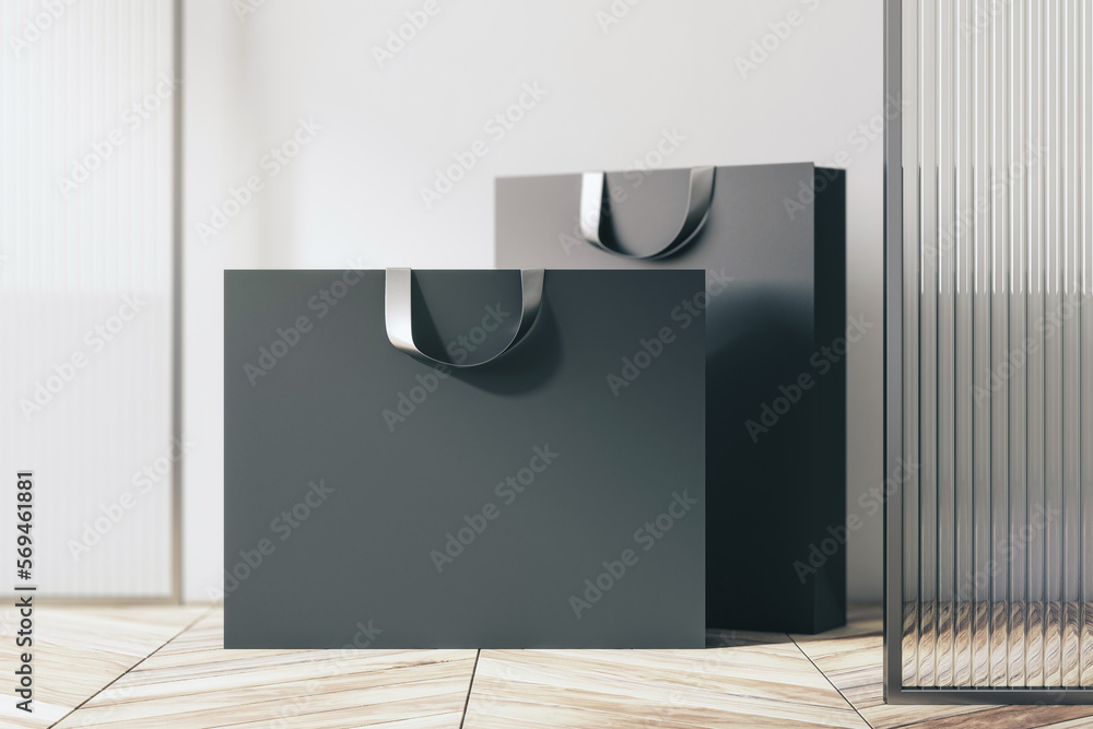 Poster front view on blank black paper shopping bags with place for your brand name or text on light wooden
