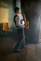 Young elegant man playing gold alto saxophone in misty room