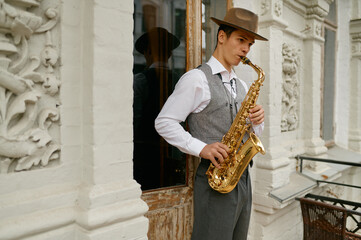 Young male musician practicing saxophone in balcony at home