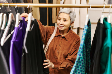 Of smiling senior woman browsing clothes on racks in boutique