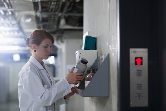 Young female engineer checking chemical bottles in a rack, Freiburg im Breisgau, Baden-W&uuml;rttemberg, Germany