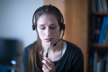 Young woman wearing headset and thinking, Freiburg im Breisgau, Baden-Württemberg, Germany