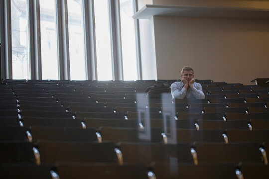 Bored college student sitting alone in lecture hall and listening lecture, Freiburg im Breisgau, Baden-Württemberg, Germany