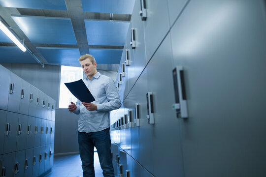 Young university student reading document file in locker room, Freiburg im Breisgau, Baden-Württemberg, Germany